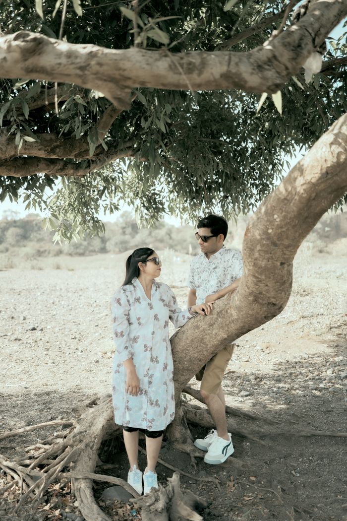A couple enjoying a sunny day under a large tree, expressing relaxation and connection.