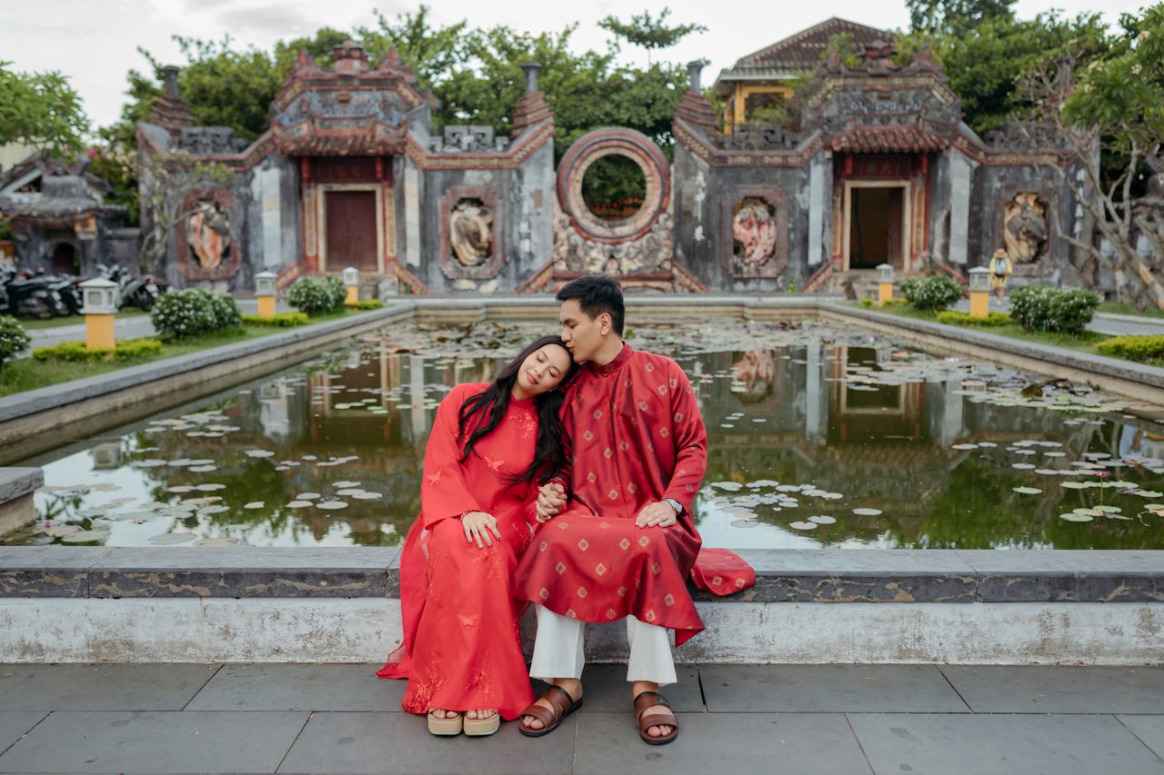 Couple embracing by a lotus pond in traditional Vietnamese attire at a temple in Đà Nẵng, Vietnam.