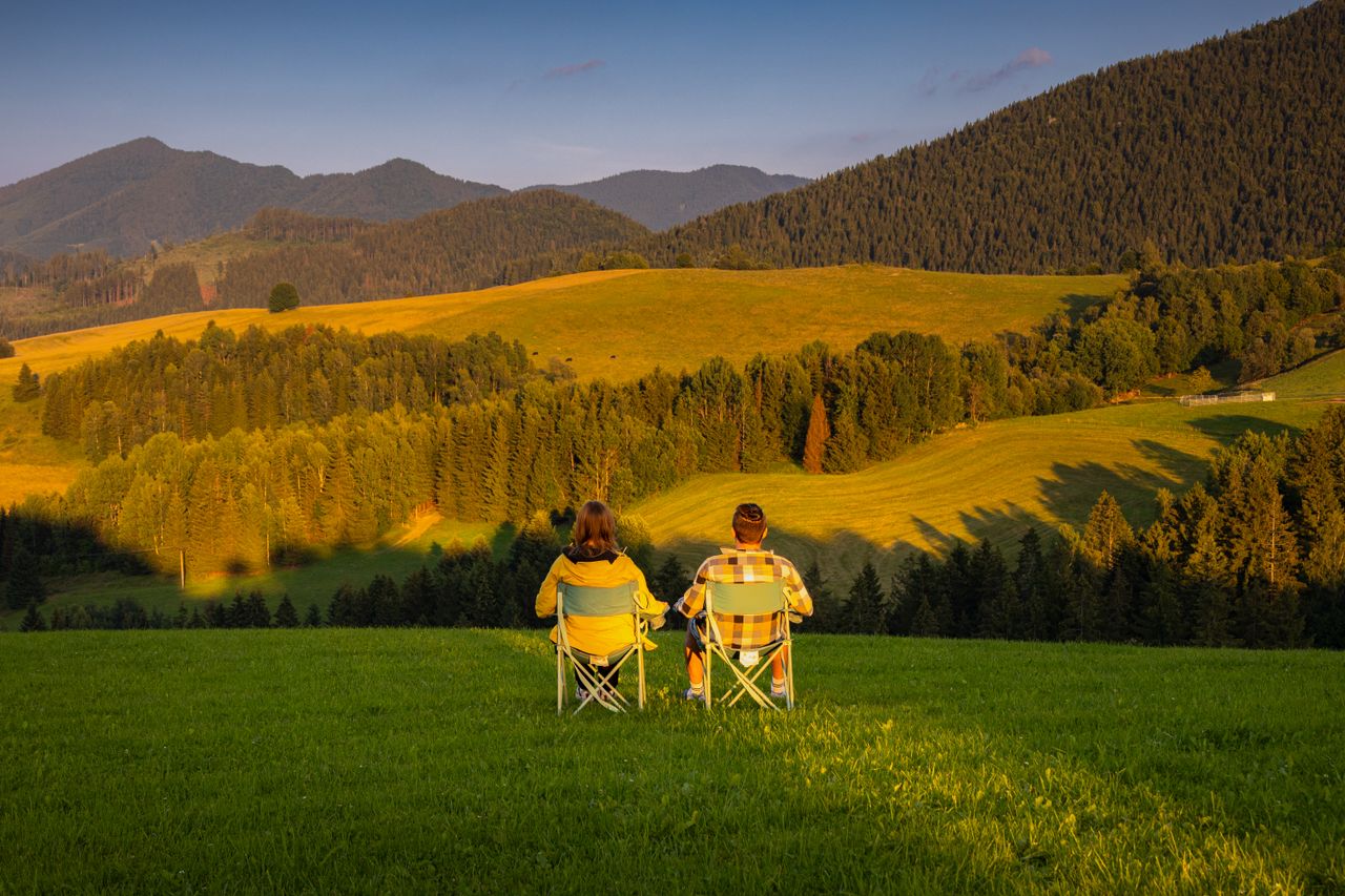 Relaxing couple enjoys a sunset view over Slovakia's tranquil mountain landscape.