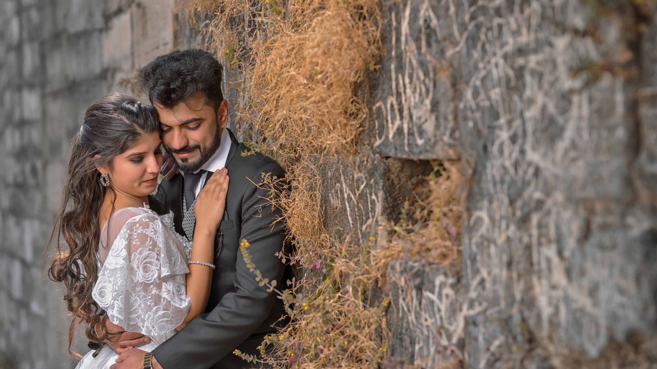 Couple in love embracing by a rustic wall, capturing a tender moment.